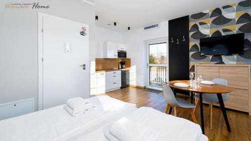 Cet appartement comprend une chambre avec un lit et une table ainsi qu'une cuisine. dans l'établissement Wonder Home - Apartamenty Halo Karkonosze z ogrodem, sezonowym basenem, placem zabaw i widokiem na Śnieżkę - zlokalizowane blisko Karpacza, à Mysłakowice