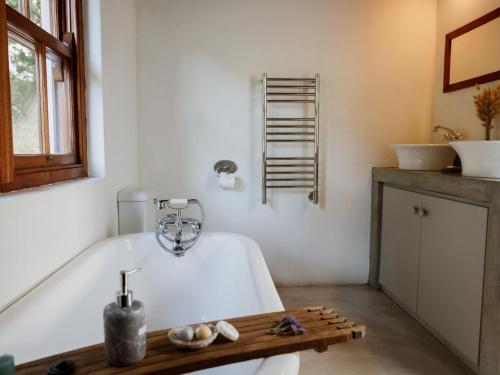 Springfontein Wine Estate في ستانفورد: حمام مع حوض استحمام ومغسلتين