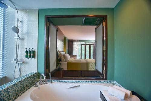 a bathroom with a tub and a large mirror at The Bihai Hua Hin in Hua Hin