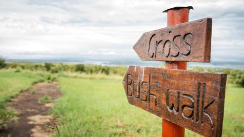 a wooden sign with the word mess on it in a field at Mama Washindi Lodge in Pakwach East