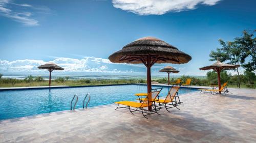 a swimming pool with chairs and umbrellas next to a pool at Mama Washindi Lodge in Pakwach East