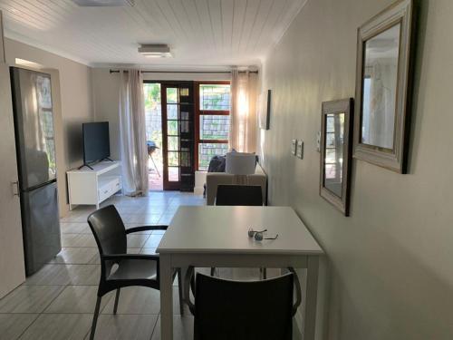 ein Wohnzimmer mit Tisch und Stühlen und einem Fernseher in der Unterkunft Jay's Snug in Knysna