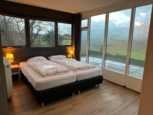 a bedroom with a large bed with a window at 't Eibernest in De Cocksdorp