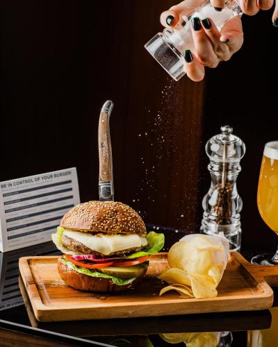 a person holding a glass of beer next to a hamburger at Hilton Baku in Baku