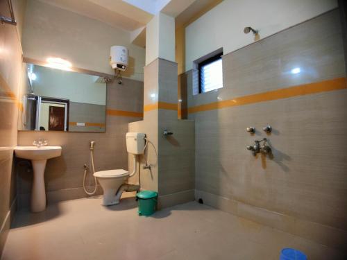 a bathroom with a toilet and a sink and a mirror at Shinjini Resort in Mandarmoni
