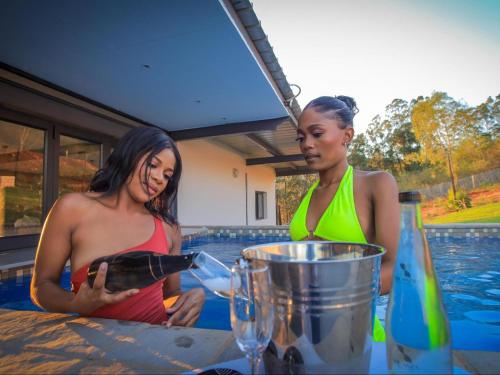two women standing at a table with a bottle of wine at The Anza Lifestyle Lodge in Louis Trichardt