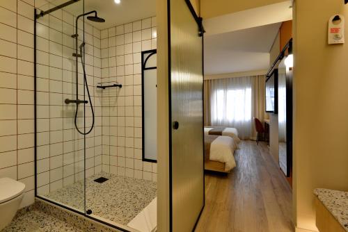 a bathroom with a shower and a toilet and a bedroom at City Lodge Hotel V&A Waterfront in Cape Town