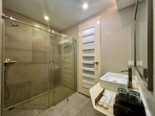 a bathroom with a glass shower and a sink at Livingston Hotel in Sandakan