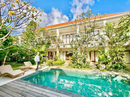 a man standing by a swimming pool in front of a building at Bali Telaga Hati Yoga Healing And Retreat Center Hostel in Sanur