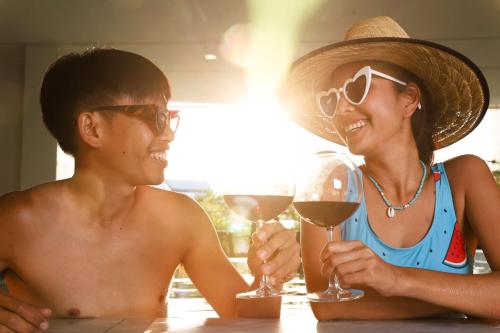 a man and woman sitting at a table with wine glasses at The Rise Suites Hotel, Chiang Mai - SHA Extra Plus in Chiang Mai