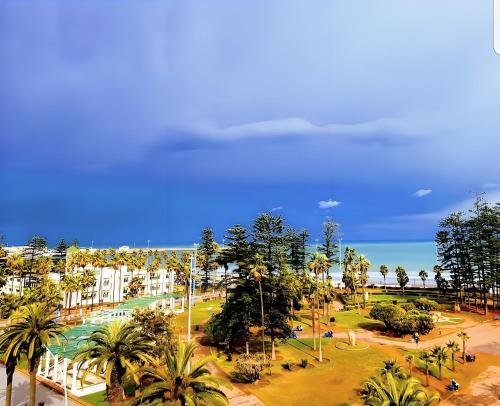 a park with palm trees and the ocean in the background at Appartement Vintage full équipé EL JADIDA in El Jadida