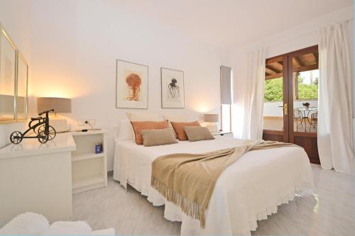 a white bedroom with a large bed and a table at Villa Bennassar in Inca