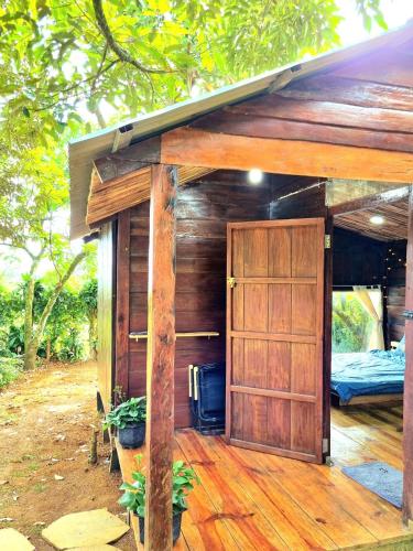 a small house with a door and a bed at Homestay Vườn Trái Cây Nhiệt Đới VÔ ƯU GARDEN in Bao Loc
