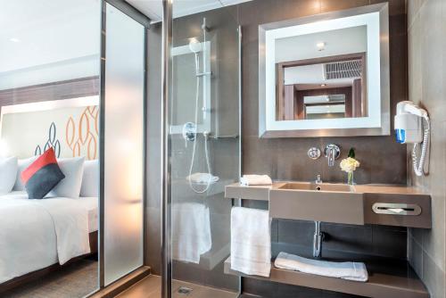 a bathroom with a shower and a sink and a bed at Hilton Garden Inn Bangkok Silom in Bangkok