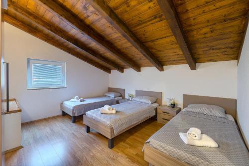 two beds in a room with wooden ceilings at Villa Parlera in Ližnjan