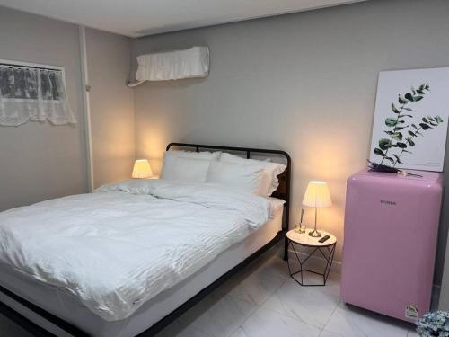 1 dormitorio con cama blanca y nevera rosa en Pet Friendly 301, en Suncheon
