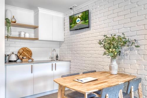 cocina con mesa de madera y pared de ladrillo blanco en Cammeray Waters, en Ashbourne