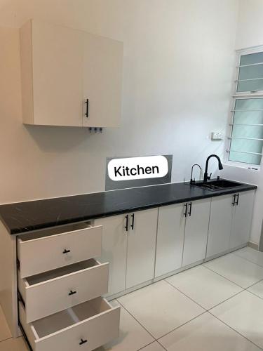 a kitchen with white cabinets and a black counter top at BEDONG GOLF VILLA in Bedung