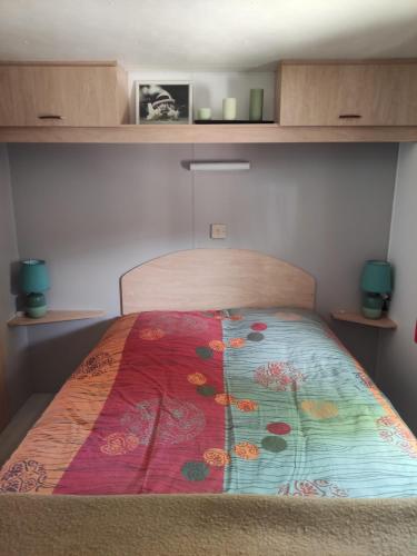 une chambre avec un lit avec une courtepointe colorée dessus dans l'établissement MOBIL HOME CAMPING 3***, à Villefranche-de-Conflent