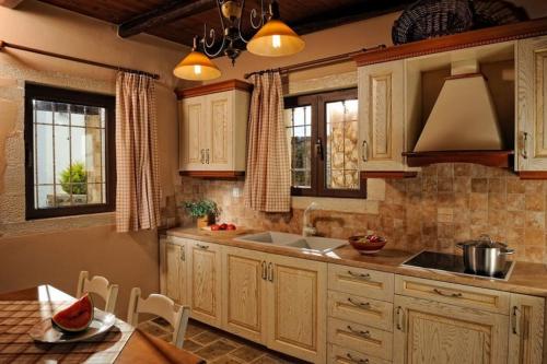 a kitchen with wooden cabinets and a sink and a table at Πέτρινο Σπίτι με Θέα Θάλασσα in Achlia