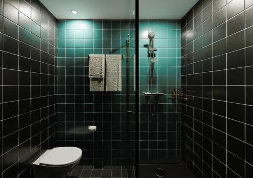 a green tiled bathroom with a toilet and a shower at The Social Hub Glasgow in Glasgow
