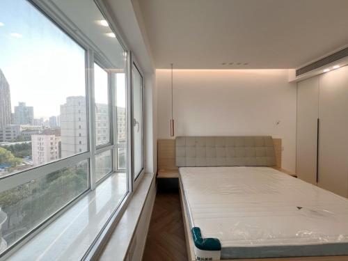 a bed in a room with a large window at Shanghai Jing'an Art Pavilion-Large 3Bedrooms South-north Direct Sunny House in Shanghai