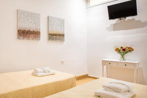 Cette chambre comprend 2 lits et une télévision murale. dans l'établissement Vener Suites, à La Canée