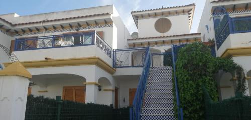 een wit huis met een blauwe leuning en een trap bij Apartamento Playa Vera in Vera