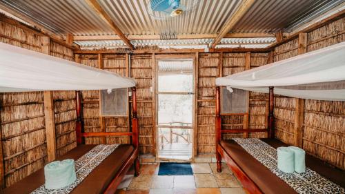 two beds in a bamboo room with a window at Mama Washindi Lodge in Pakwach East