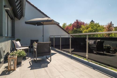 a patio with chairs and an umbrella on a balcony at Miralior Apartment Mainz - perfekt für Business, Familie, Weinproben im Herbst! in Mainz