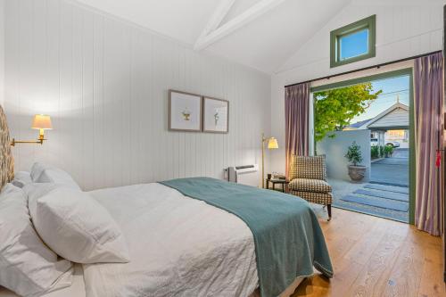 een slaapkamer met een bed en een deur naar een patio bij Augusta Hut in Auckland