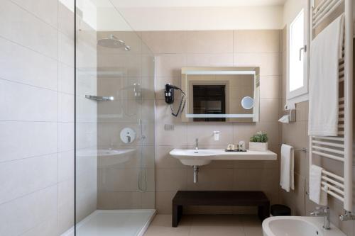 y baño blanco con lavabo y ducha. en Hotel Vespucci, en Porto Cesareo