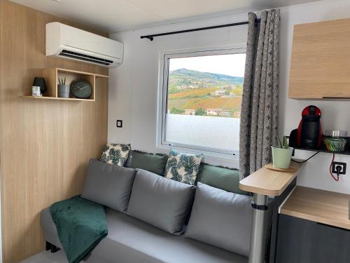 - un canapé dans une petite chambre avec fenêtre dans l'établissement Le Bouchon de Liège, à Beaujeu