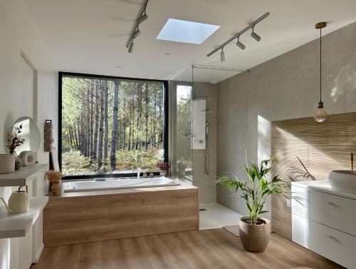 a bathroom with a tub and a large window at Villa au coeur de la forêt in Mano