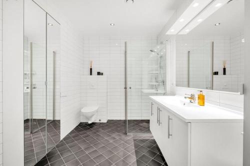 a white bathroom with a sink and a shower at Moderne sentralt hjem in Tromsø