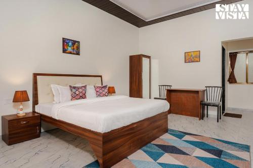 a bedroom with a bed and a desk in it at Mango Splash by VEO - Part of StayVista in Karjat