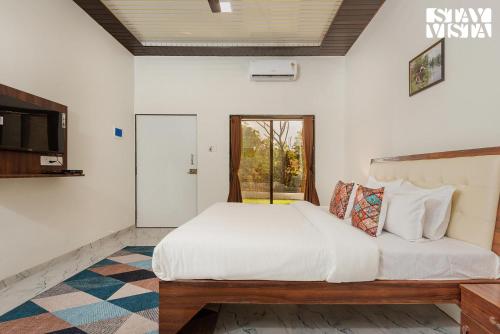 a bedroom with a large white bed and a window at Mango Splash by VEO - Part of StayVista in Karjat