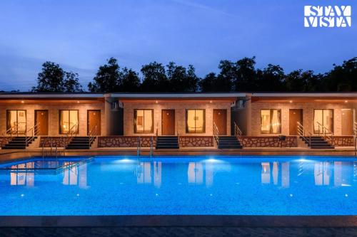 a swimming pool in front of a building at night at Mango Splash by VEO - Part of StayVista in Karjat