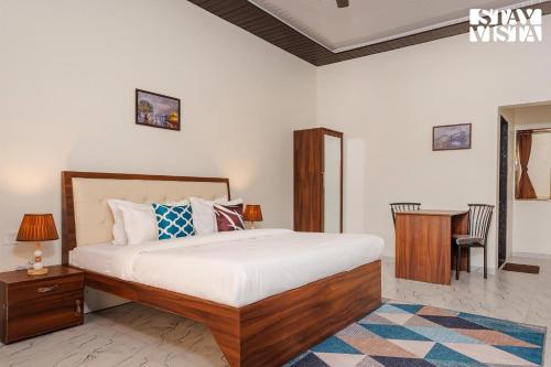 a bedroom with a bed and a desk and a table at Mango Splash by VEO - Part of StayVista in Karjat
