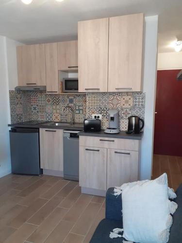 une cuisine avec des armoires blanches et un comptoir dans l'établissement Studio climatisé avec une place de parking et classé 2 étoiles à la Faviére, à Bormes-les-Mimosas