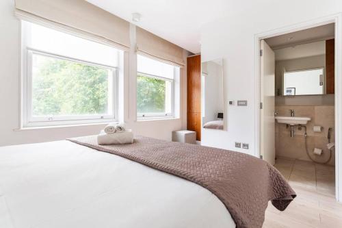 a white bedroom with a large bed and a bathroom at Beautiful 2-Bed Apartment in Central London in London
