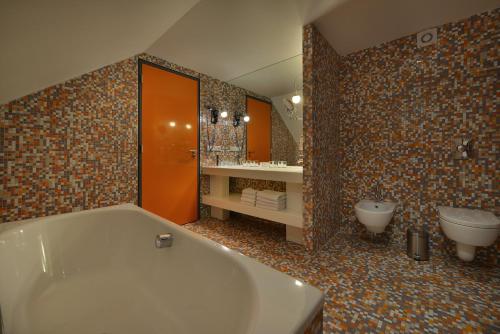 uma casa de banho com uma banheira, um WC e um lavatório. em Omnia Hotel Relax & Wellness em Janske Lazne