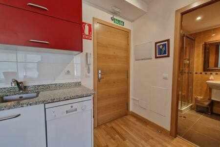 une cuisine avec évier et une porte menant à une salle de bains. dans l'établissement Apartamento con piscina, à Llanes