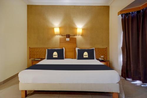 a bedroom with a large bed with blue and white pillows at Super Townhouse Oak Orchard Hotel in Pune
