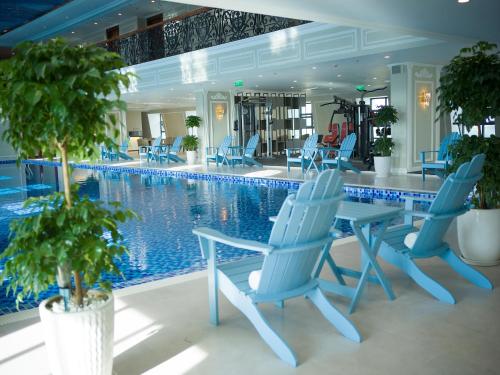 a swimming pool with blue chairs and a table and a swimming pool at MerPerle Dalat Hotel in Da Lat