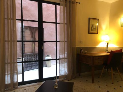 Riad Inaya Fez في فاس: غرفة مع مكتب ونافذة كبيرة مطلة على ساحة الفناء
