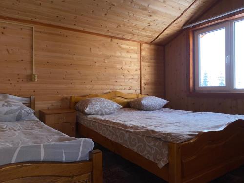um quarto com 2 camas num chalé de madeira em Котедж Краєвид em Yablunytsya