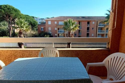 een tafel en stoelen op een balkon met uitzicht op een gebouw bij Splendide T3 "Santa Barbara" Piscine clim parking in Cavalaire-sur-Mer