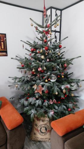 a christmas tree with ornaments in a living room at CASA de VIS in Sinaia