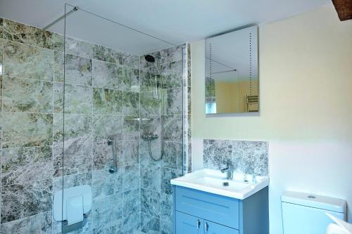 a bathroom with a shower and a sink and a mirror at Finest Retreats - The Walton in Onibury